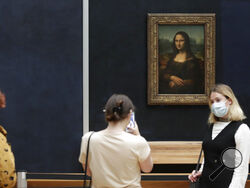 FILE - Visitors pose in front of Leonardo da Vinci's Mona Lisa in the Louvre museum, Wednesday, May, 19, 2021 in Paris. A man seemingly disguised as an old woman in a wheelchair threw a piece of cake at the glass protecting the Mona Lisa on Sunday May 29, 2022 at the Louvre Museum and shouted at people to think of planet Earth. (AP Photo/Thibault Camus, File)