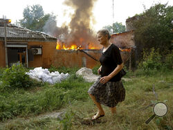 FILE - A woman runs from a house that's on fire after shelling in Donetsk, on the territory which is under the Government of the Donetsk People's Republic control, eastern Ukraine, Friday, June 3, 2022. Day after day, Russia is pounding the Donbas region of Ukraine with relentless artillery and air raids, making slow but steady progress to seize the industrial heartland of its neighbor. With the conflict now in its fourth month, it’s a high-stakes campaign that could dictate the course of the entire war. (A