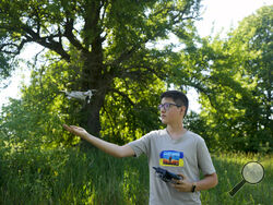 Andriy Pokrasa, 15, lands his drone on his hand during an interview with The Associated Press in Kyiv, Ukraine, Saturday, June 11, 2022. Andriy is being hailed in Ukraine for stealthy aerial reconnaissance work he has done with his dad in the ongoing war with Russia. They used their drone to help the country's military spot, locate and destroy Russian targets in the early days of the Russian invasion. (AP Photo/Natacha Pisarenko)