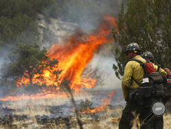 FILE - Hot shot crew members keep an eye on the blaze as fire crews ignite the underbrush off of Forest Road 545B in an effort to contain the Pipeline Fire near Flagstaff, Arizona on June 15, 2022. Firefighter groups are applauding steps taken by the Biden administration to temporarily raise wages for the men and women on the front lines of the nation's largest wildfires. (Rachel Gibbons/Arizona Daily Sun via AP, File)