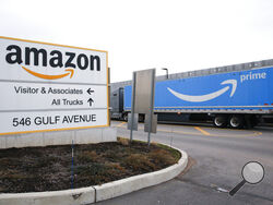 FILE - An Amazon Prime truck passes by a sign outside an Amazon fulfillment center on Staten Island, New York, on March 19, 2020. Amazon is heading into its annual Prime Day sales event on Tuesday, July 12, 2022, much differently than how it entered the pandemic. Once the darling of the pandemic economy, the company posted a rare quarterly loss in April as well as its slowest rate of revenue growth in nearly two decades at 7%. (AP Photo/Kathy Willens, File)