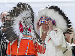 Pope Francis puts on an indigenous headdress during a meeting with indigenous communities, including First Nations, Metis and Inuit, at Our Lady of Seven Sorrows Catholic Church in Maskwacis, near Edmonton, Canada, Monday, July 25, 2022. Pope Francis begins a "penitential" visit to Canada to beg forgiveness from survivors of the country's residential schools, where Catholic missionaries contributed to the "cultural genocide" of generations of Indigenous children by trying to stamp out their languages, cultu