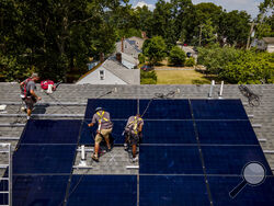 FILE - Employees of NY State Solar, a residential and commercial photovoltaic systems company, install an array of solar panels on a roof, Thursday, Aug. 11, 2022, in the Long Island hamlet of Massapequa, N.Y. Americans are less concerned now about how climate change might impact them personally — and about how their personal choices affect the climate than they were three years ago, according to a according to a June poll from The Associated Press-NORC Center for Public Affairs Research. (AP Photo/John Min
