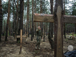 Oleg Kotenko, the Commissioner for Issues of Missing Persons under Special Circumstances uses his smartphone to film the unidentified graves of civilians and Ukrainian soldiers in the recently retaken area of Izium, Ukraine, Thursday, Sept. 15, 2022 who had been killed by Russian forces near the beginning of the war. A mass grave of Ukrainiansoldiers and unknown buried civilians was found in the forest of recently recaptured city ofIzium. (AP Photo/Evgeniy Maloletka)