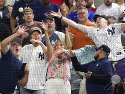 Fans reach for a foul ball by New York Yankees' Aaron Judge during the second inning in the second baseball game of a doubleheader against the Texas Rangers in Arlington, Texas, Tuesday, Oct. 4, 2022. (AP Photo/LM Otero)