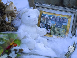 Flowers, a stuffed animal, and a framed image featuring the photos of the four people found dead at a house on Nov. 13, 2022 in Moscow, Idaho, rest in the snow in front of the house on Tuesday, Nov. 29, 2022. The university will be holding a system-wide vigil, Wednesday evening, Nov. 30, 2022 in memory of the students, as investigators continue to look for a suspect and motive in the killings. (AP Photo/Ted S. Warren)
