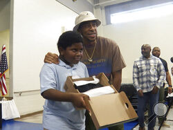 Rapper and actor Ludacris, right, smiles with a student who received new shoes at Miles Intermediate Elementary School in Atlanta on Wednesday, Dec. 7, 2022. (AP Photo/Sharon Johnson)