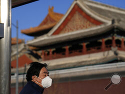 A resident wears a mask as he stands near the Lama Temple in Beijing, Tuesday, Dec. 27, 2022. Companies welcomed China's decision to end quarantines for travelers from abroad as an important step to revive slumping business activity while Japan on Tuesday announced restrictions on visitors from the country as infections surge. (AP Photo/Ng Han Guan)