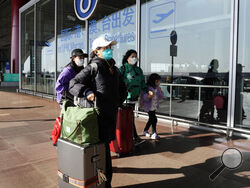 FILE - Passengers wearing masks walk through the Capital airport terminal in Beijing on Dec. 13, 2022. On Wednesday, Dec. 28, 2022, the U.S. announced new COVID-19 testing requirements for all travelers from China, joining other nations imposing restrictions because of a surge of infections. (AP Photo/Ng Han Guan, File)