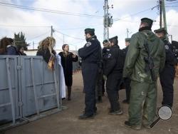 Settlers talk to Israeli police in Amona outpost, Wednesday, Feb. 1, 2017. The military issued eviction orders the day before telling residents to evacuate Amona within 48 hours and blocked roads leading to the outpost. Thousands of soldiers and police gathered around Amona early Wednesday morning. (AP Photo/Oded Balilty)