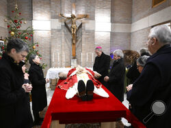 n this image released on Monday, Jan. 2, 2023, by the Vatican Media news service, Bishop George Gaenswein, center, and close entourage pray in front of the body of late Pope Emeritus Benedict XVI lying out in state in the chapel of the monastery 'Mater Ecclesiae' where he mostly lived after retiring on Feb. 28, 2013. Pope Benedict, the German theologian who will be remembered as the first pope in 600 years to resign, has died, the Vatican announced Saturday, Dec. 31, 2022. He was 95. (Vatican Media via AP)