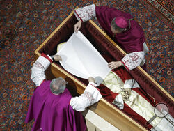 In this image released on Thursday, Jan. 5, 2023, by the Vatican Media news service, Bishops Georg Gaenswein, right, and Diego Ravelli cover the face of Pope Emeritus Benedict XVI with a white silk veil as he rests in a cypress coffin in St. Peter's Basilica, Wednesday, Jan. 4, 2023, the night before his funeral mass presided over by Pope Francis at the Vatican. Benedict died at 95 on Dec. 31 in the monastery on the Vatican grounds where he had spent nearly all of his decade in retirement. He was 95. (Vatic
