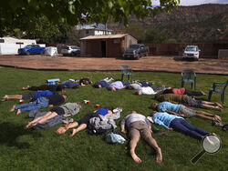 Participants lay face down on the grass during an integration circle at an ayahuasca retreat in Hildale, Utah, on Saturday, Oct. 15, 2022. Following each of the three ayahuasca ceremonies, Hummingbird Church asks their participants to partake in integration, or a group reflection and discussion, to help interpret messages they received from the ayahuasca. (AP Photo/Jessie Wardarski)