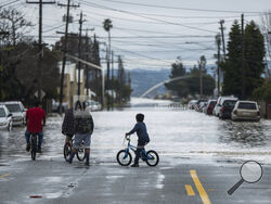 People look at heavy floodwaters in Watsonville, Calif., Saturday, March 11, 2023. Gov. Gavin Newsom has declared emergencies in 34 counties in recent weeks, and the Biden administration approved a presidential disaster declaration for some on Friday morning, a move that will bring more federal assistance. (AP Photo/Nic Coury)