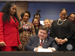 Illinois Gov. J.B. Pritzker signs into law the Paid Leave For All Workers Act as Illinois House Speaker pro-tem Jehan Gordon Booth, left, Lt. Gov. Juliana Stratton, second from left, and Senate Majority Leader Kimberly Lightford, right, watch on Monday, March 13, 2023, in Chicago. Illinois became one of three U.S. states to require employers to offer paid time off for any reason starting in January of 2024. (AP Photo/Charles Rex Arbogast)