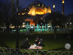 People break their fast after dusk on the first day of Ramadan backdropped by the iconic Byzantine-era Hagia Sophia mosque in Istanbul, Turkey, Thursday, March 23, 2023. Abstaining from all food and drink -- not even a sip of water is allowed-- and sexual intercourse from dawn to sunset during the Muslim holy month of Ramadan is regarded as an act of piety and devotion to God and an exercise in self-restraint. (AP Photo/Francisco Seco)