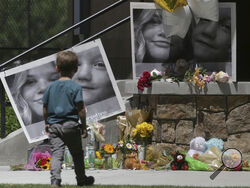 FILE - A boy looks at a memorial for Tylee Ryan and Joshua "JJ" Vallow in Rexburg, Idaho, on June 11, 2020. The investigation started roughly 29 months ago with two missing children. It soon grew to encompass five states, four suspected murders and claims of an unusual, doomsday-focused religious beliefs involving "dark spirits" and "zombies." On Monday, April 10, 2023, an Idaho jury will begin the difficult task of deciding the veracity of those claims and others in the triple murder trial of Lori Vallow D