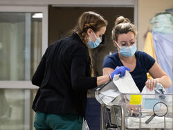 In a photo provided by the University of Vermont Health Network, licensed nursing assistant Jordan Bushy, right, and a student nurse care for newborns at the University of Vermont Children’s Hospital in Burlington, Vt., Friday, April 28, 2023. Research led by Dr. Leslie Young of the children’s hospital has found that babies born to opioid users had shorter hospital stays and needed less medication when their care emphasized parent involvement, skin-to-skin contact and a quiet environment. (Ryan Mercer/Unive