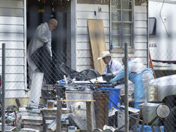 Law enforcement authorities removing bodies from a scene where five people were shot the night before Saturday, April 29, 2023, in Cleveland, TX. Authorities say an 8-year-old child was among five people killed in a shooting at the home in southeast Texas late Friday night. (Yi-Chin Lee/Houston Chronicle via AP)