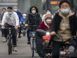 FILE - Commuters wearing face masks ride bicycles along a street in the central business district in Beijing, Thursday, Oct. 20, 2022. The World Health Organization downgraded its assessment of the coronavirus pandemic on Friday, May 5, 2023, saying it no longer qualifies as a global emergency. (AP Photo/Mark Schiefelbein, File)