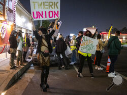 File - A protester identified as "Reagan" holds a sign outside the Star Garden Topless Dive Bar on Saturday, March 26, 2022 in the North Hollywood area of Los Angeles. Dancers at the bar, who have for 15 months been seeking safer workplace conditions, better pay and health insurance, among other benefits, are poised to become the only unionized group of strippers in the U.S. (Francine Orr/Los Angeles Times via AP)