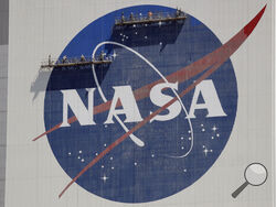 FILE - Workers on scaffolding repaint the NASA logo near the top of the Vehicle Assembly Building at the Kennedy Space Center in Cape Canaveral, Fla., May 20, 2020. (AP Photo/John Raoux, File)