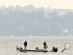 Fishermen, surrounded by a smoky haze, spend an afternoon on Owasco Lake, Tuesday, June 6, 2023, in Owasco, N.Y. Smoke from Canada's wildfires has been moving into the United States since last month. The most recent fires near Quebec have been burning for at least several days. (Kevin Rivoli/The Citizen via AP)