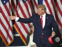 FILE - Former President Donald Trump tosses caps to the crowd as he steps onstage during a rally at the Macomb Community College Sports & Expo Center in Warren, Mich., Saturday, Oct. 1, 2022. Trump is set to appear in Michigan on Sunday for one of his first public appearances since a federal indictment earlier this month. The former president will speak just outside Detroit at the Oakland County GOP’s Lincoln Day Dinner where he will be honored by the party as the “Man of the Decade.” (Todd McInturf/Detroit