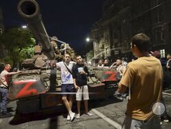 Servicemen of the Wagner Group military company sit atop of a tank, as local civilians pose for a photo prior to their leave an area at the HQ of the Southern Military District in a street in Rostov-on-Don, Russia, Saturday, June 24, 2023. Kremlin spokesman Dmitry Peskov said that Yevgeny Prigozhin's troops who joined him in the uprising will not face prosecution and those who did not will be offered contracts by the Defense Ministry. After the deal was reached Saturday, Prigozhin ordered his troops to halt