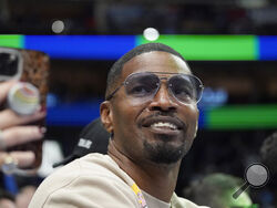 FILE - Jamie Foxx smiles during an NBA basketball game between the Washington Wizards and Dallas Mavericks in Dallas, Saturday, Nov. 27, 2021. Academy Award winning actor, Grammy winning singer and comedian says he “went to hell and back” but is recovering from an undisclosed medical condition. Foxx made his first public comments in an Instagram message posted on Friday, July 21, 2023 after being hospitalized in April. (AP Photo/LM Otero, File)