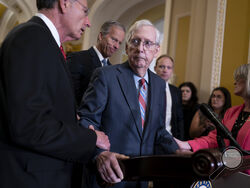 U.S. Senate Minority Leader Mitch McConnell, R-Ky., center, is helped by, from left, Sen. John Barrasso, R-Wyo., Sen. John Thune, R-S.D., and Sen. Joni Ernst, R-Iowa, after the 81-year-old GOP leader froze at the microphones as he arrived for a news conference, Wednesday, July 26, 2023, at the Capitol in Washington. (AP Photo/J. Scott Applewhite)