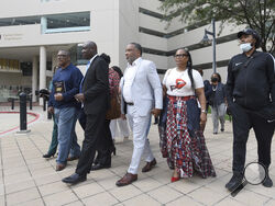 FILE - Attorney Ben Crump, second from left, walks with Ron Lacks, left, Alfred Lacks Carter, third from left, both grandsons of Henrietta Lacks, and other descendants of Lacks, outside the federal courthouse in Baltimore, Oct. 4, 2021. The family of Henrietta Lacks is settling a lawsuit against a biotechnology company it accuses of improperly profiting from her cells. Their federal lawsuit in Baltimore claimed Thermo Fisher Scientific has made billions from tissue taken without the Black woman’s consent fr