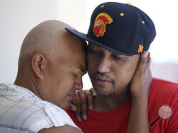JP Mayoga, right, a chef at the Westin Maui, Kaanapali, and his wife, Makalea Ahhee, hug on their balcony at the hotel and resort, Sunday, Aug. 13, 2023, near Lahaina, Hawaii. About 200 employees are living there with their families. Officials urge tourists to avoid traveling to Maui as many hotels prepare to house evacuees and first responders on the island where a wildfire demolished a historic town and killed dozens of people. (AP Photo/Rick Bowmer)