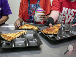 FILE - Second-grade students select their meals during lunch break in the cafeteria, Dec. 12, 2022, at an elementary school in Scottsdale, Ariz. More students in schools serving low-income communities will be eligible to receive breakfast and lunch at no cost under a rule change announced Tuesday, Sept. 26, 2023, by the U.S. Department of Agriculture. (AP Photo/Alberto Mariani, File)