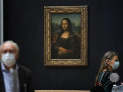 FILE - Journalists walk past Leonardo da Vinci's Mona Lisa during a visit of the Louvre museum Tuesday, June 23, 2020. Using X-rays to peer into the chemical structure of a tiny speck of the celebrated work of art, scientists have gained new insight into the techniques that Leonardo da Vinci used to paint his groundbreaking portrait of the woman with the exquisitely enigmatic smile. (AP Photo/Christophe Ena, File)