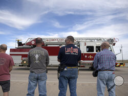 Lubbock county first responders pause as the procession for Fritch Fire Chief Zeb Smith passes by, Tuesday, March 5, 2024, in Lubbock, Texas. Smith suffered a medical emergency and died while fighting a fire Tuesday. (Annie Rice/Lubbock Avalanche-Journal via AP)