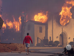  AP Photo/Chris Pizzello A man walks in front of the burning Altadena Community Church Wednesday in the downtown Altadena section of Pasadena, California.