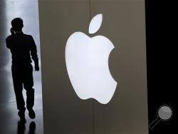 In this Sept. 5, 2014, file photo, a Chinese man talking on his phone walks into an Apple store in Beijing. Apple is poised to reveal its next big thing Tuesday, Sept. 9 in a crucial attempt to prove its technological tastemakers still have the power to mesmerize the masses. (AP Photo/Andy Wong, File)
