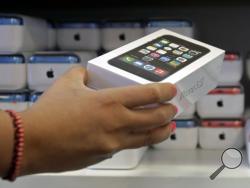 In this Friday, Sept. 20, 2013, file photo, a sales person pulls out an iPhone 5s for a customer during the opening day of sales of the iPhone 5s and iPhone 5C, in Hialeah, Fla. Apple says Monday, Sept. 23, 2013, that shoppers snapped up 9 million of its newest iPhones since the devices were launched Friday, and that demand is exceeding supply. (AP Photo/Alan Diaz)