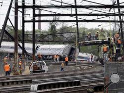 Emergency personnel walk near the scene of a deadly train wreck, Wednesday, May 13, 2015, in Philadelphia. Federal investigators arrived Wednesday to determine why an Amtrak train jumped the tracks in Tuesday night's fatal accident. (AP Photo/Mel Evans)