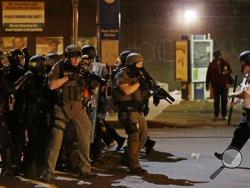 Police in riot gear fall back after arresting a protester for violating a curfew imposed in the aftermath of rioting following Monday's funeral for Freddie Gray, who died in police custody, Friday, May 1, 2015, in Baltimore. (AP Photo/David Goldman)