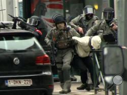 In this framegrab taken from VTM, armed police officers escort a suspect to a police vehicle during a raid in the Molenbeek neighborhood of Brussels, Belgium, Friday March 18, 2016. After an intense four-month manhunt across Europe and beyond, police on Friday captured Salah Abdeslam, the top fugitive in the Paris attacks in the same Brussels neighborhood where he grew up. (VTM via AP)