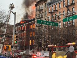 New York City firefighters work the scene of a large fire and a partial building collapse in the East Village neighborhood of New York on Thursday, March 26, 2015. Orange flames and black smoke are billowing from the facade and roof of the building near several New York University buildings. (AP Photo/Suzanne Mitchell)