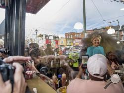 As seen through a window, Democratic presidential candidate Hillary Clinton greets patrons at Cedar Park Cafe in Philadelphia, Sunday, Nov. 6, 2016. (AP Photo/Andrew Harnik)