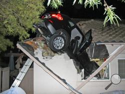 This photo provided by homeowner George Strother shows a sport utility vehicle that went airborne and sailed into the roof of his home in Escondido, Calif., around 12:30 a.m. Wednesday, Dec. 10, 2014. (AP Photo/George Strother)