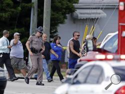 A Florida state trooper, center, escorts a group of parents to a day care center to pick up their children after a vehicle crashed into the center, Wednesday, April 9, 2014, in Winter Park, Fla. At least 15 people were injured, including children. (AP Photo/John Raoux)