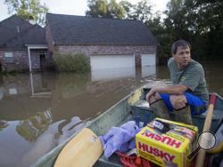 David Key boats away from his flooded home after reviewing the damage in Prairieville, La., Tuesday, Aug. 16, 2016. Key, an insurance adjuster, fled his home as the flood water was rising with his wife and three children and returned today to assess the damage. (AP Photo/Max Becherer)