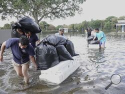 People try and save valuables, wading through high flood waters in a Fort Lauderdale, Fla., neighborhood on Thursday, April 13, 2023. South Florida is keeping a wary eye on a forecast that calls for rain a day after nearly a foot fell in a matter of hours. The rains caused widespread flooding, closed the Fort Lauderdale airport and turned thoroughfares into rivers. (Joe Cavaretta/South Florida Sun-Sentinel via AP)