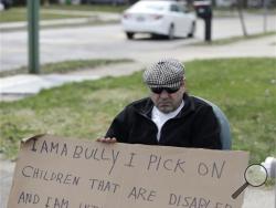 Edmond Aviv sits on a street corner holding a sign Sunday, April 13, 2014, in South Euclid, Ohio declaring he's a bully, a requirement of his sentence because he was accused of harassing a neighbor and her disabled children for the past 15 years. Municipal Court Judge Gayle Williams-Byers ordered Aviv, 62, to display the sign for five hours Sunday. 