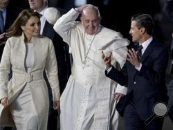 Pope Francis' skullcap flies off as he walks with Mexico's President Enrique Pena Nieto and first lady Angelica Rivera upon arrival to Benito Juarez International Airport in Mexico City, Friday, Feb. 12, 2016. The pontiff is in Mexico for a week-long visit. (AP Photo/Eduardo Verdugo)